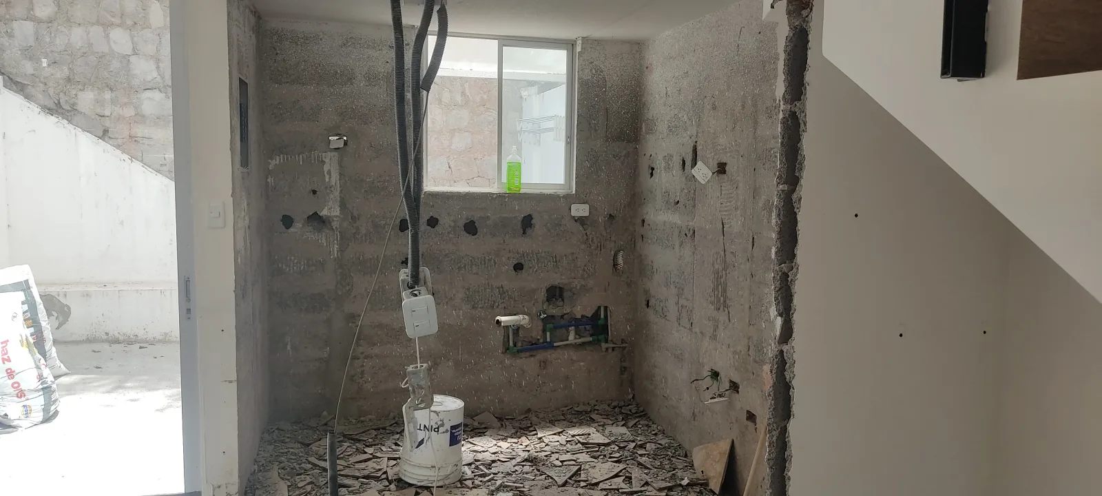 Área de cocina en obra gris durante canalización eléctrica y preparación de paredes