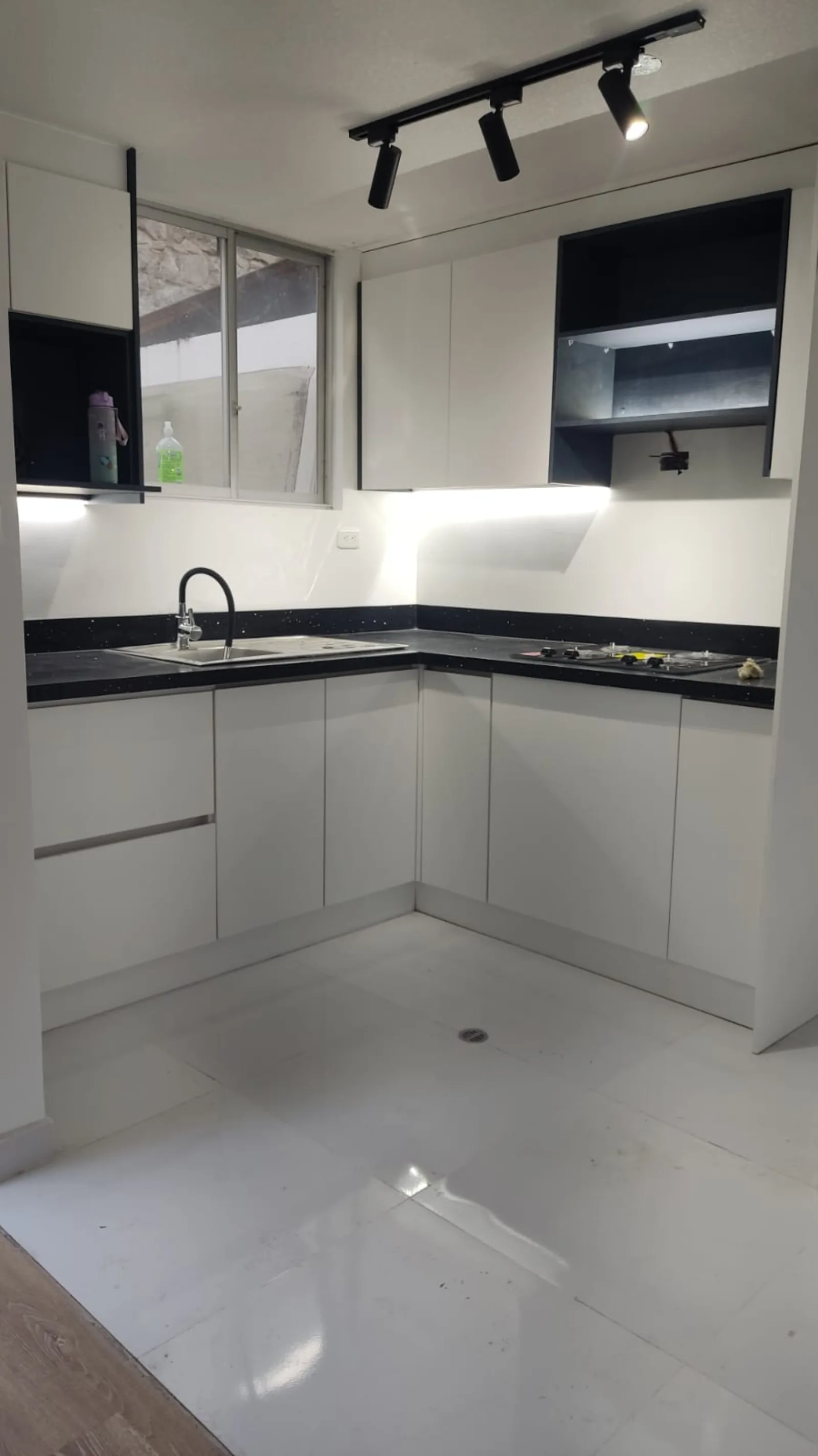 Cocina remodelada con gabinetes superiores, mesón negro e iluminación LED bajo mueble