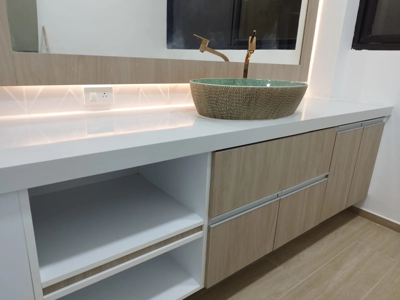 Lavabo sobrepuesto en piedra verde con grifería dorada en baño remodelado de Grünenthal