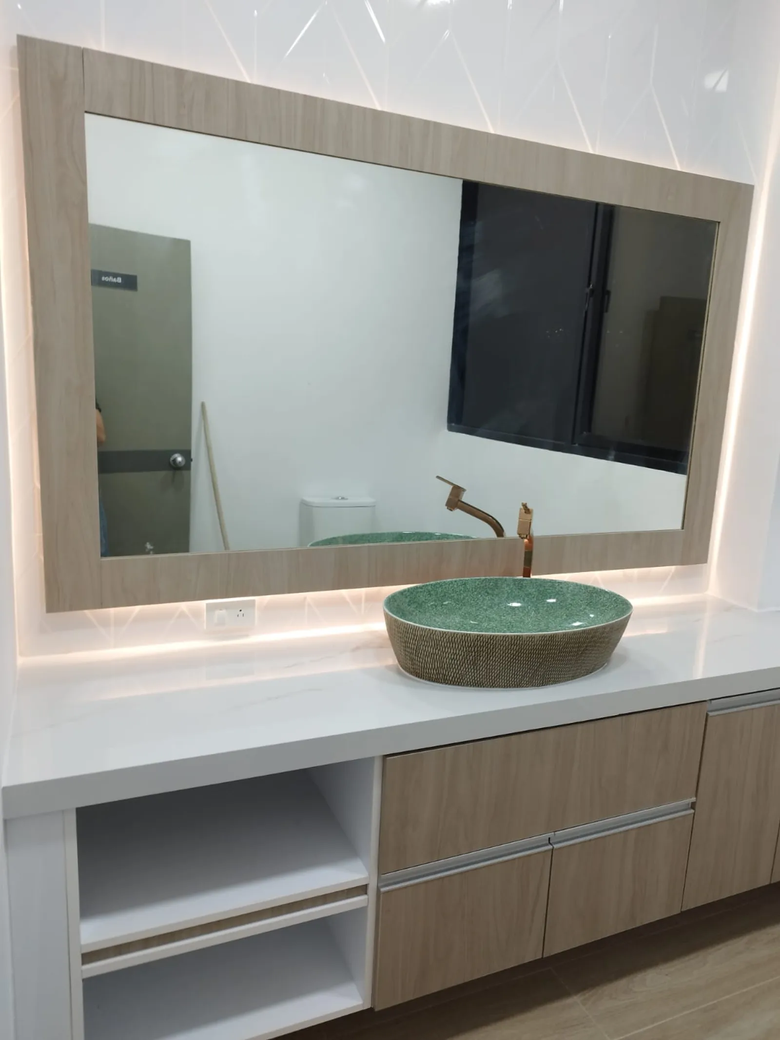 Vista completa de baño ejecutivo con espejo retroiluminado y lavabo en piedra verde
